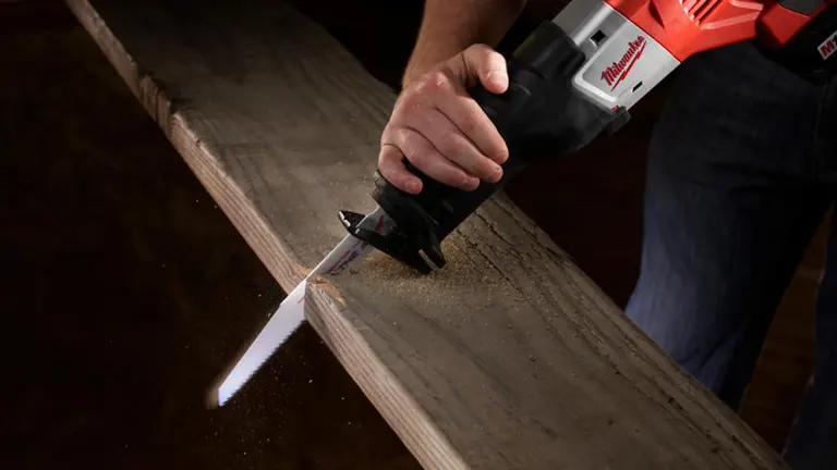 Close-up of a person using a Milwaukee reciprocating saw to cut wood