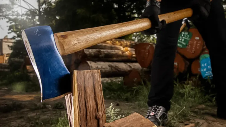 person is using a Husqvarna S21 Wooden Handle Splitting Maul to split a piece of wood
