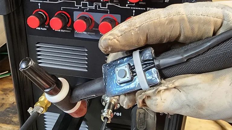 Person in welding gloves adjusting settings on a PRIMEWELD TIG225X 225 Amp Tig/Stick Welder Machine