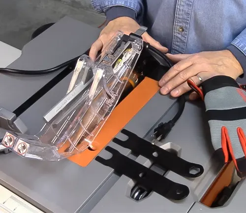 Person holding a RIDGID 10 Inch Table Saw R4510 with orange and black accents in a workshop