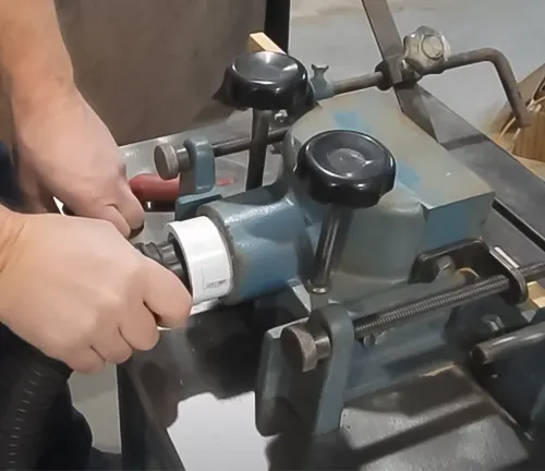 Close-up of a person using the blue Reliant Heavy Duty Wood Spindle Shaper DD34