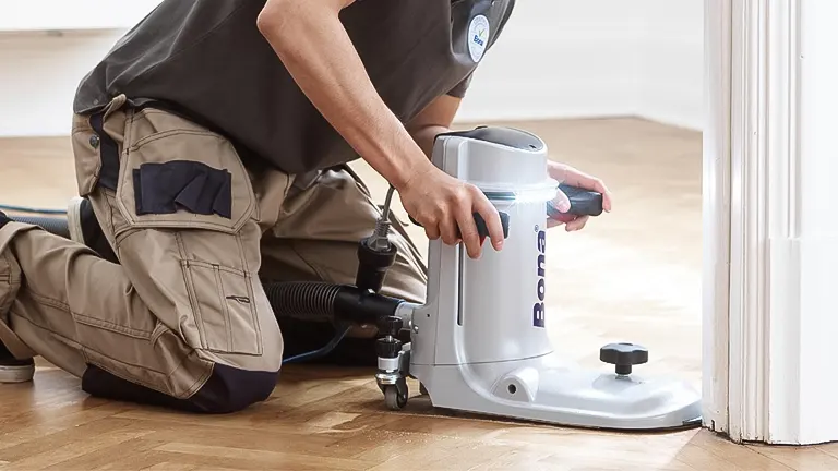 Person using a Bona floor edger to sand a wooden floor