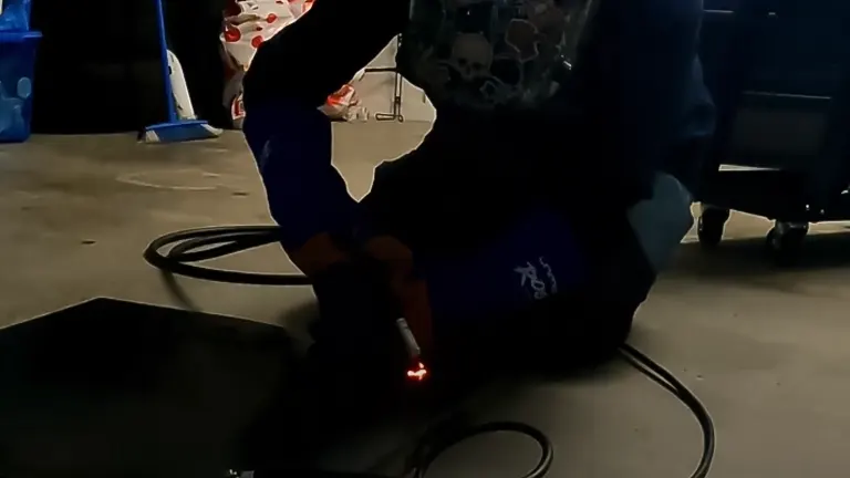 A person using a UNIMIG Viper 185 welder in a dimly lit workspace