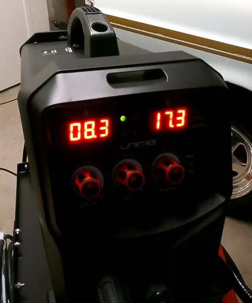 UNIMIG Viper 185 welder displaying red digital readings with control knobs, in a workshop setting