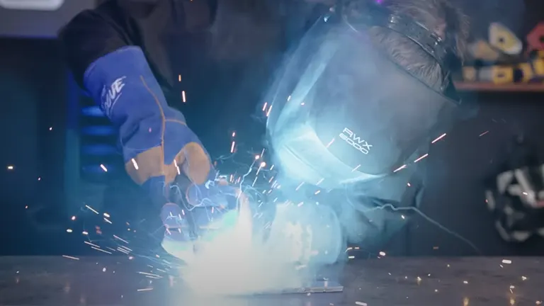 A person using a UniMig 180 Portable MIG Welder, emitting bright light and sparks