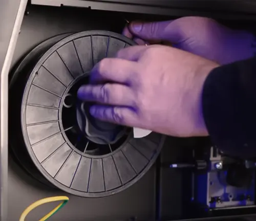 Hands adjusting a spool inside a UniMig 180 Portable MIG Welder