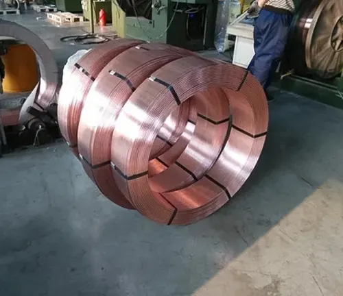 Large, round coils of shiny, copper-colored welding electrodes in a warehouse setting