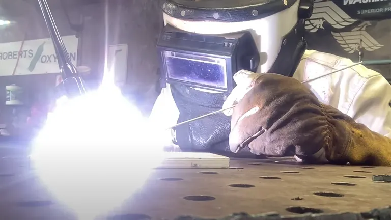 a welder using the Weldpro Digital TIG 200GD Welder Machine with bright light illuminating the work area