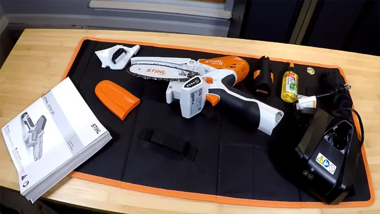 STIHL GTA 26 mini chainsaw and accessories displayed on a black and orange mat