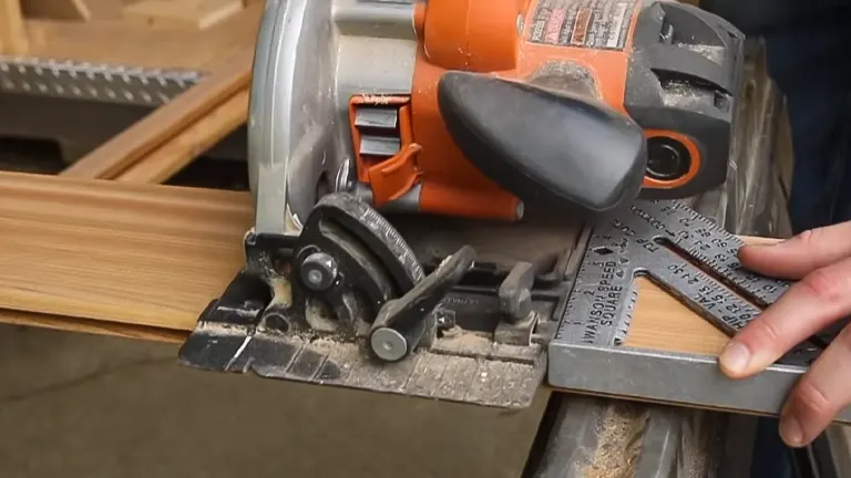 A close-up of an orange circular saw cutting through a wooden plank with a metal guide.