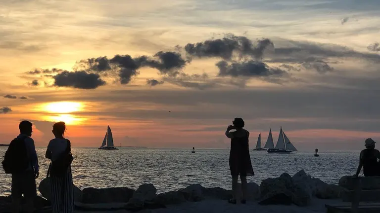 People watching the sunset with sailboats on the horizon at Fort Zachary Taylor Historic State Park
