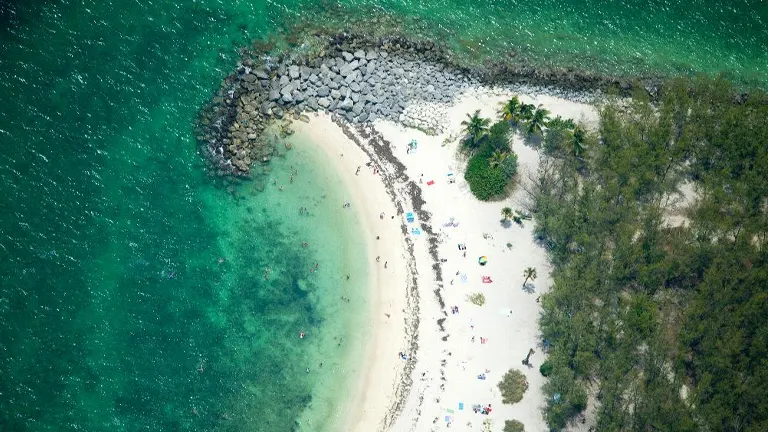 Aerial view of Fort Zachary Taylor Historic State Park beach with turquoise waters and visitors enjoying the sandy shore
