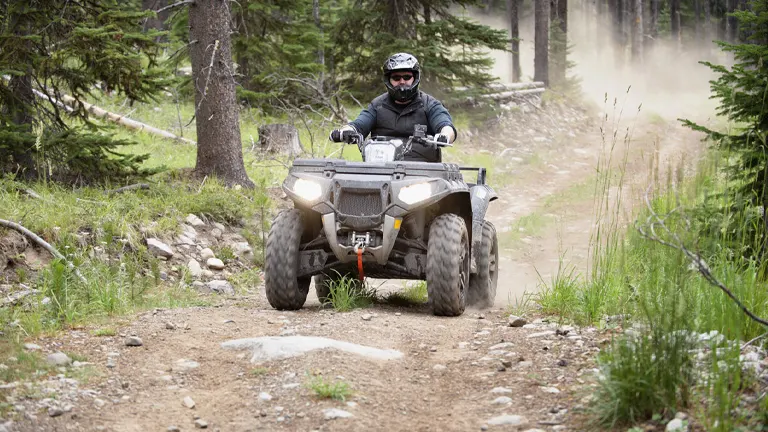 Person riding an ATV on a rugged trail in the woods