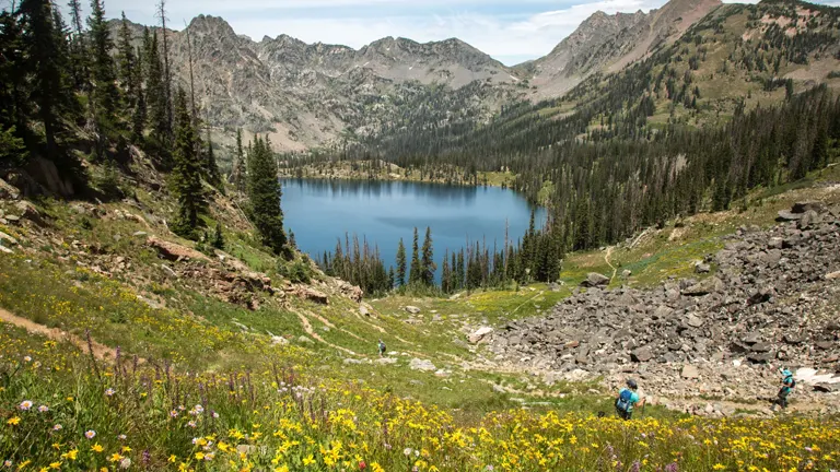 a scenic view of Zirkel Wilderness Area, featuring a serene lake surrounded by lush greenery and rugged mountains