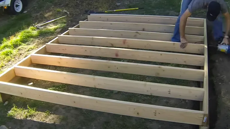A person constructing a wooden raised garden bed outdoors.

