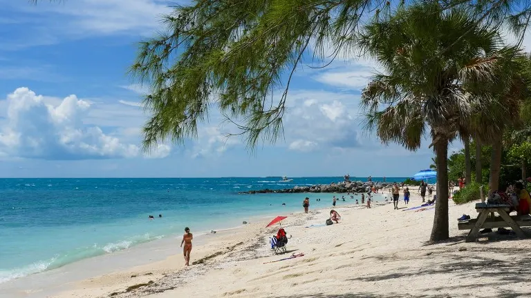 A scenic view of Fort Zachary Taylor Historic State Park with people enjoying the sandy beach, clear blue waters, and sunny skies