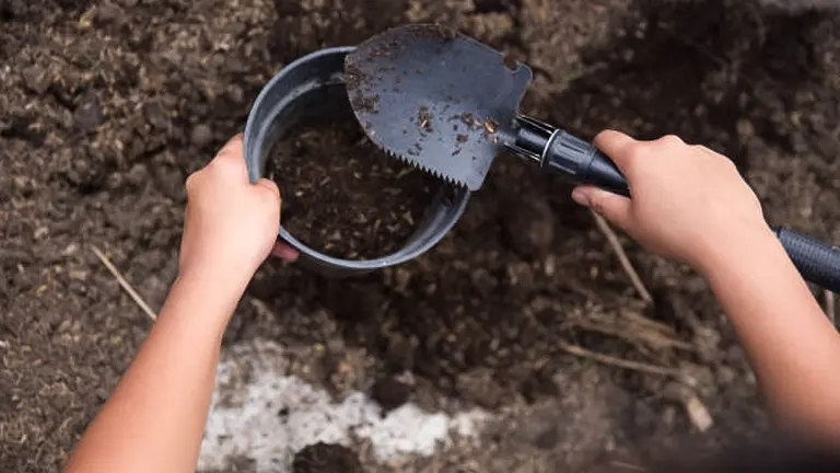 Hands using a small shovel to fill a pot with soil for raised bed gardening
