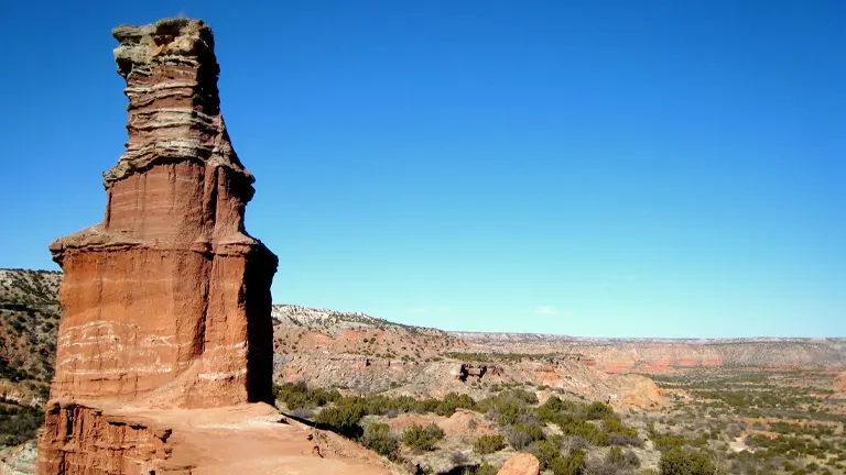 a large, distinct red rock formation in the foreground of Palo Duro Canyon State Park
