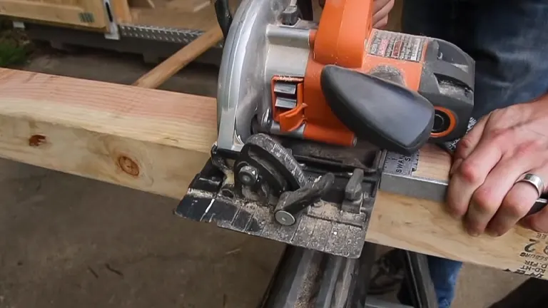 A circular saw in action, cutting through a long wooden beam on a workbench.