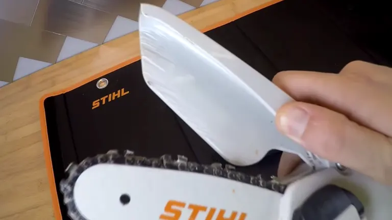 Hand holding a STIHL GTA 26 mini chainsaw over its case