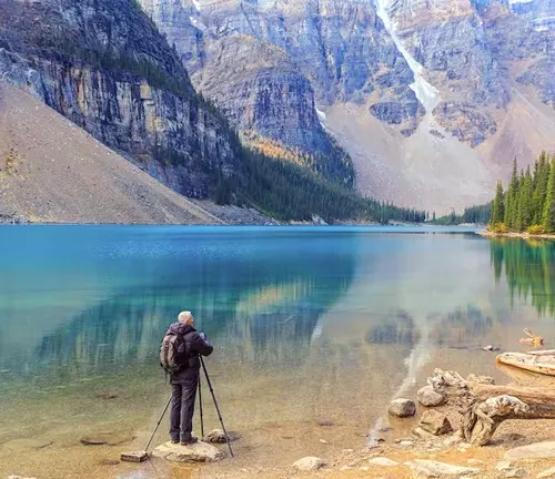 Photographer capturing a turquoise mountain lake surrounded by towering peaks