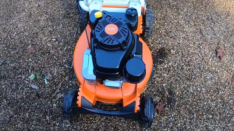 Top view of an orange and black STIHL RM 756 YC lawn mower on a gravel surface