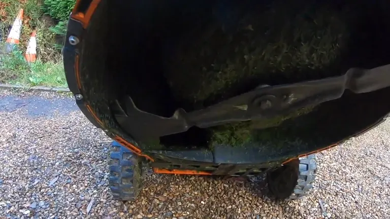 Underside view of a STIHL RM 756 YC lawn mower showing the blade and grass clippings.