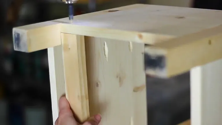 A person assembling a wooden box using a screwdriver to fasten corners.