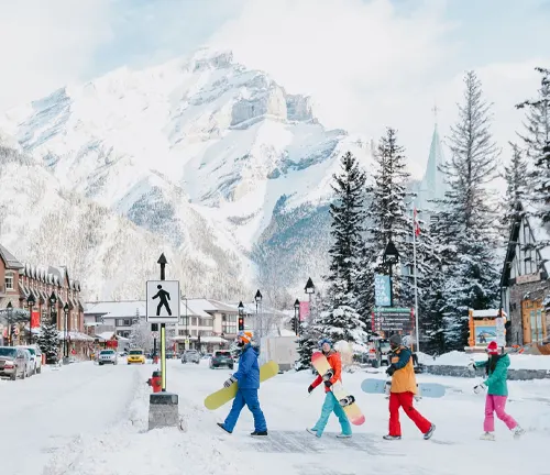 Tourists carrying snowboards in a snowy mountain village