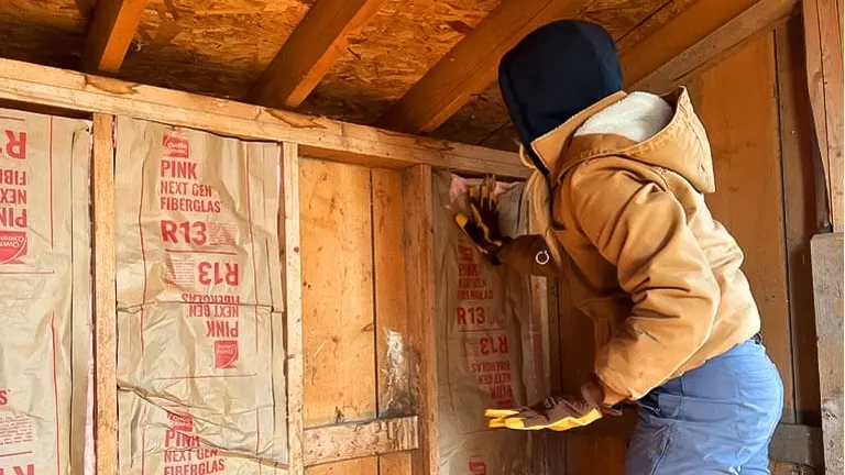a person putting interior panels in the chicken coop