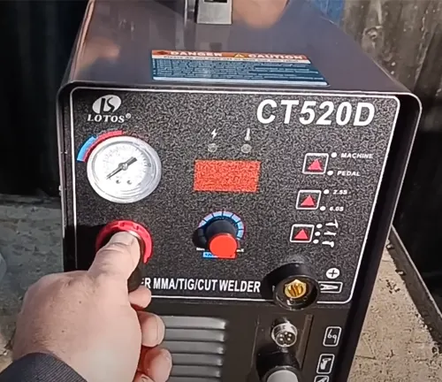 Person adjusting settings on a Lotos CT520D welder machine