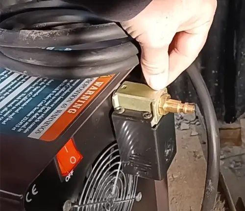 Person adjusting a brass fitting on a machine with warning labels