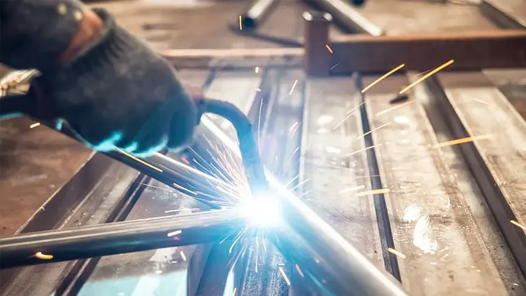 Welder working on metal pieces with bright sparks flying
