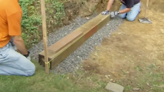How to Build a Retaining Wall with Landscape Timbers installing first layer of timbers