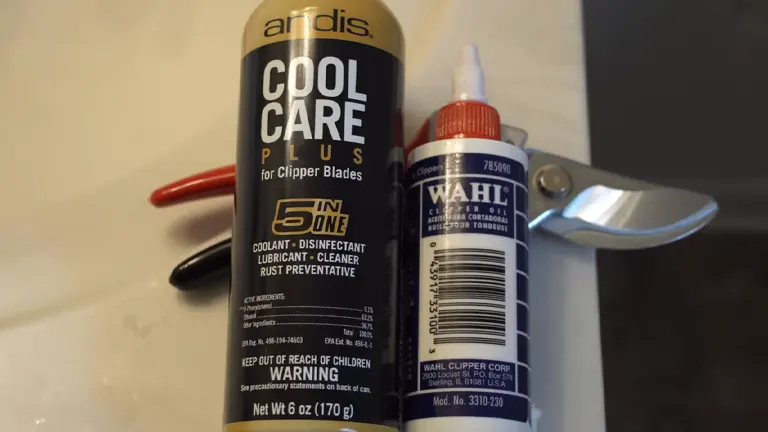 A can of Andis Cool Care Plus for clipper blades and a bottle of Wahl clipper oil, with a pair of garden shears and red-handled scissors in the background.