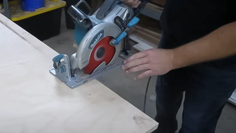 Person using a circular saw with an attached saw guide to make a straight cut on plywood