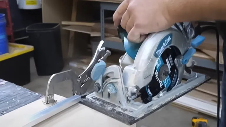 Hand operating a circular saw with a clamp-on guide for cutting plywood