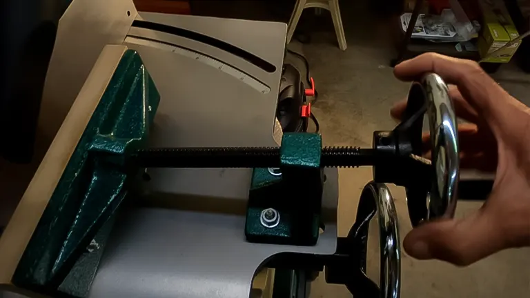 Hand adjusting the wheel on a Grizzly G0448 heavy-duty mortiser with work clamp in place
