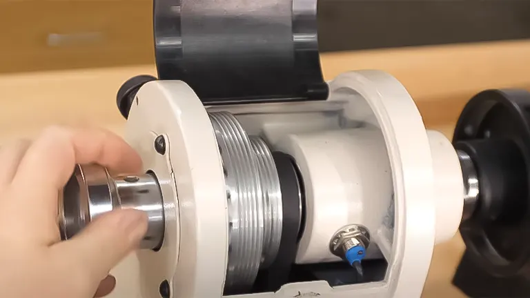 Close-up of a hand adjusting the spindle on a Grizzly G0844 lathe