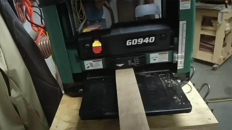 Grizzly G0940 benchtop planer with a wood plank on the feed table