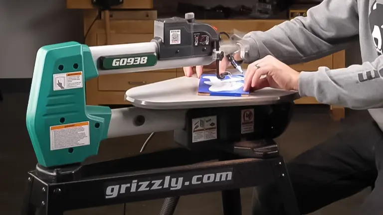 Person using the Grizzly Industrial G0938 scroll saw on a stand to cut a blue patterned piece of wood