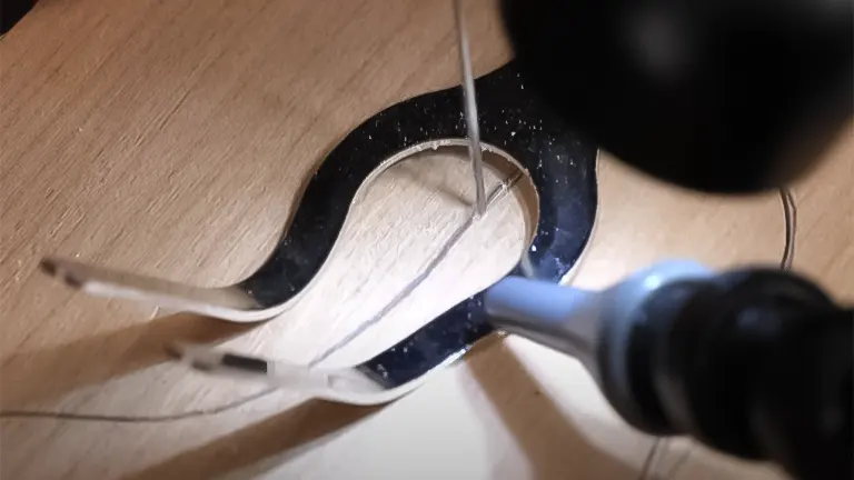 Close-up of a scroll saw blade cutting a detailed pattern through a piece of wood