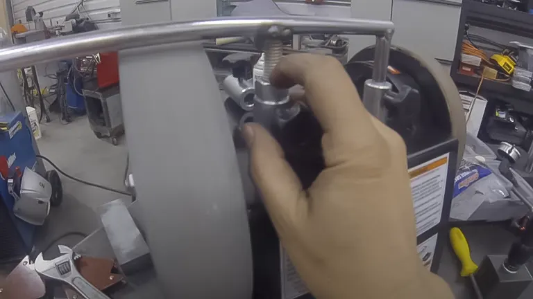 Hand adjusting a tool on a Grizzly Wet Sharpener in a workshop