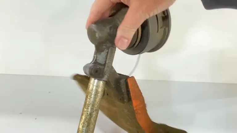 Hand using a compact trimmer on a clamped metallic rod in an indoor workspace.