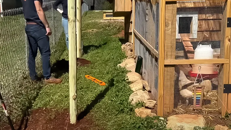 Person building a chicken run with mesh walls and a wooden frame