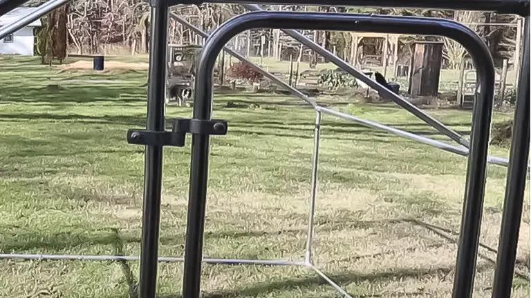 Metal coop frame with a view of a grassy field through it