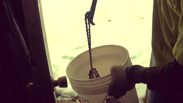 Person Removing the Chainsaw chain in the white bucket using crowbar 
