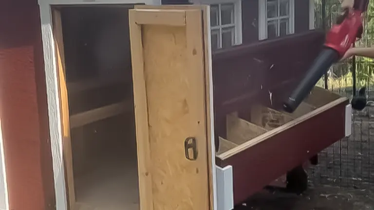 Vacuuming the interior of an open chicken coop nesting box