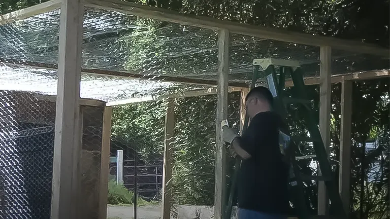 Person working on a chicken coop with protective mesh