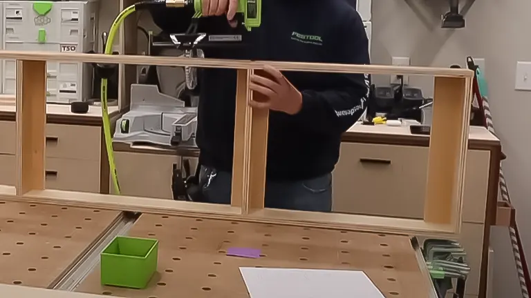 Individual securing a wooden frame with a cordless drill in a workshop